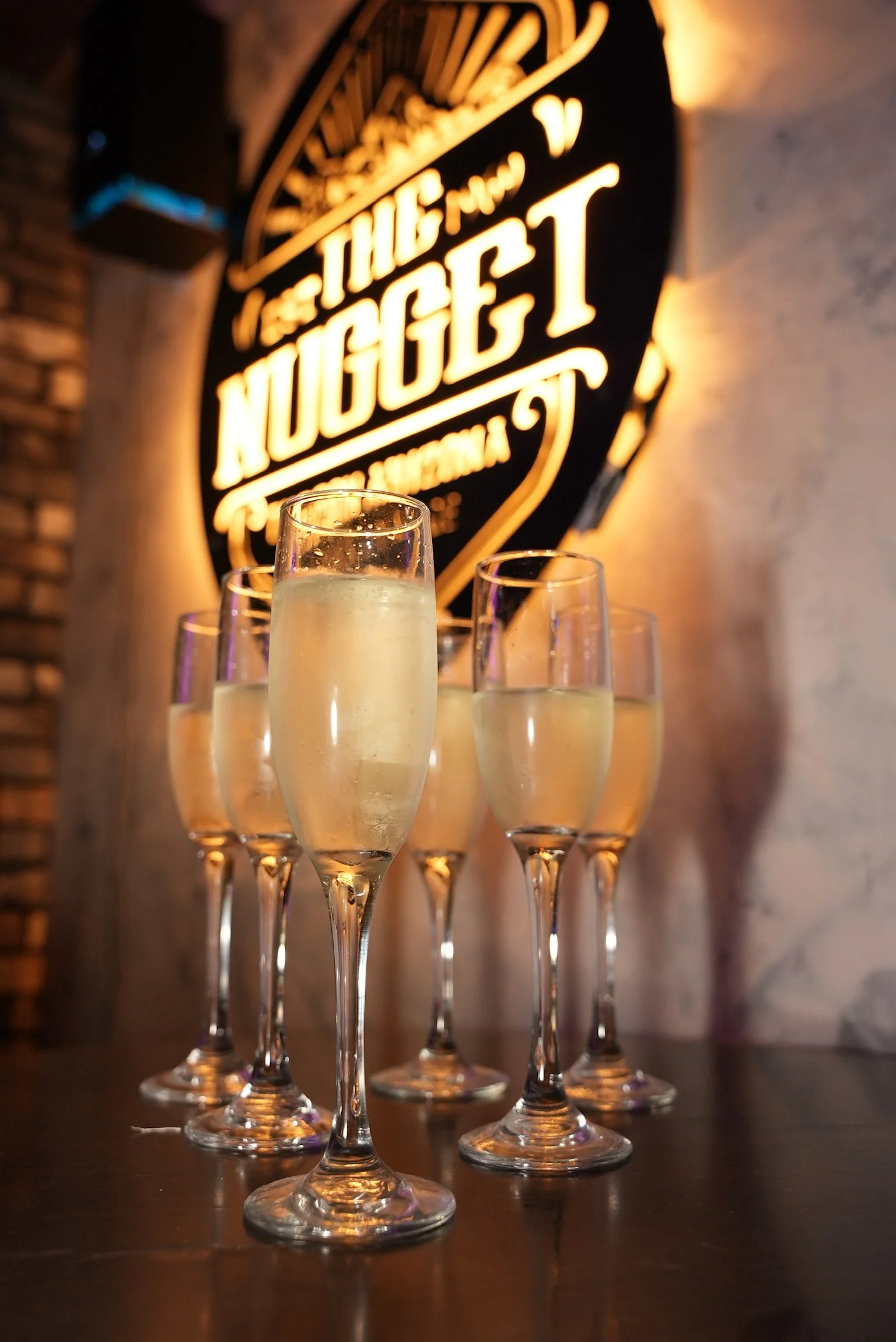 The Nugget sign glowing behind a row of champagne glasses